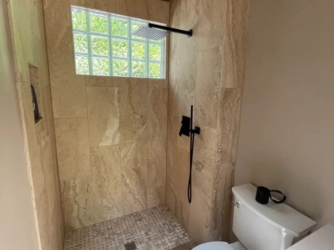 White tile shower with gold fixtures and octagonal window Oregon