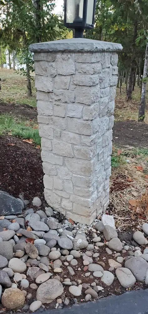 Outdoor stacked stone veneer mailbox pillar with river rock landscaping Oregon
