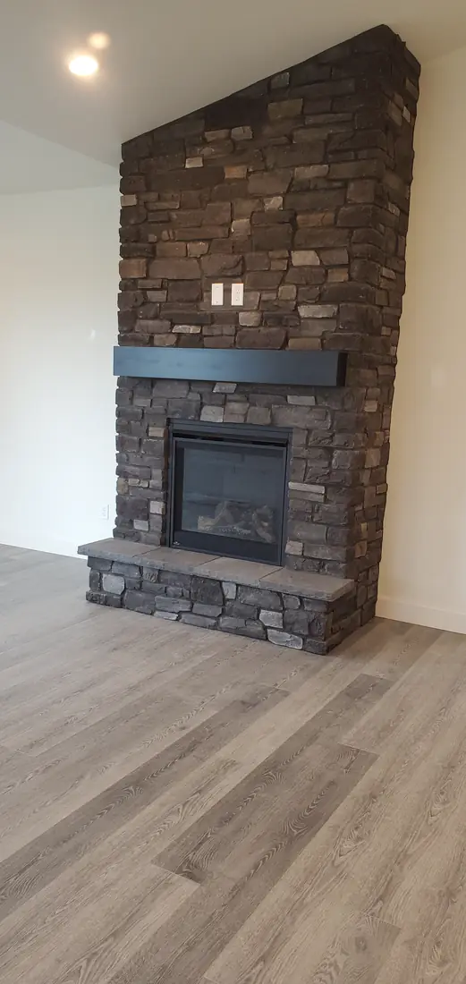 Dark gray stacked stone veneer fireplace surround with hardwood floor Oregon