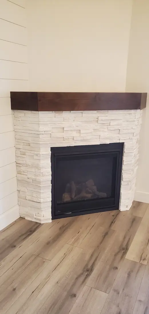 White stacked stone veneer fireplace with wood mantel and firebox Oregon